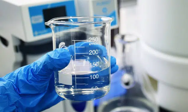laboratory equipment, 250 ml beaker glass in hand holding with gloves, chemicals products.